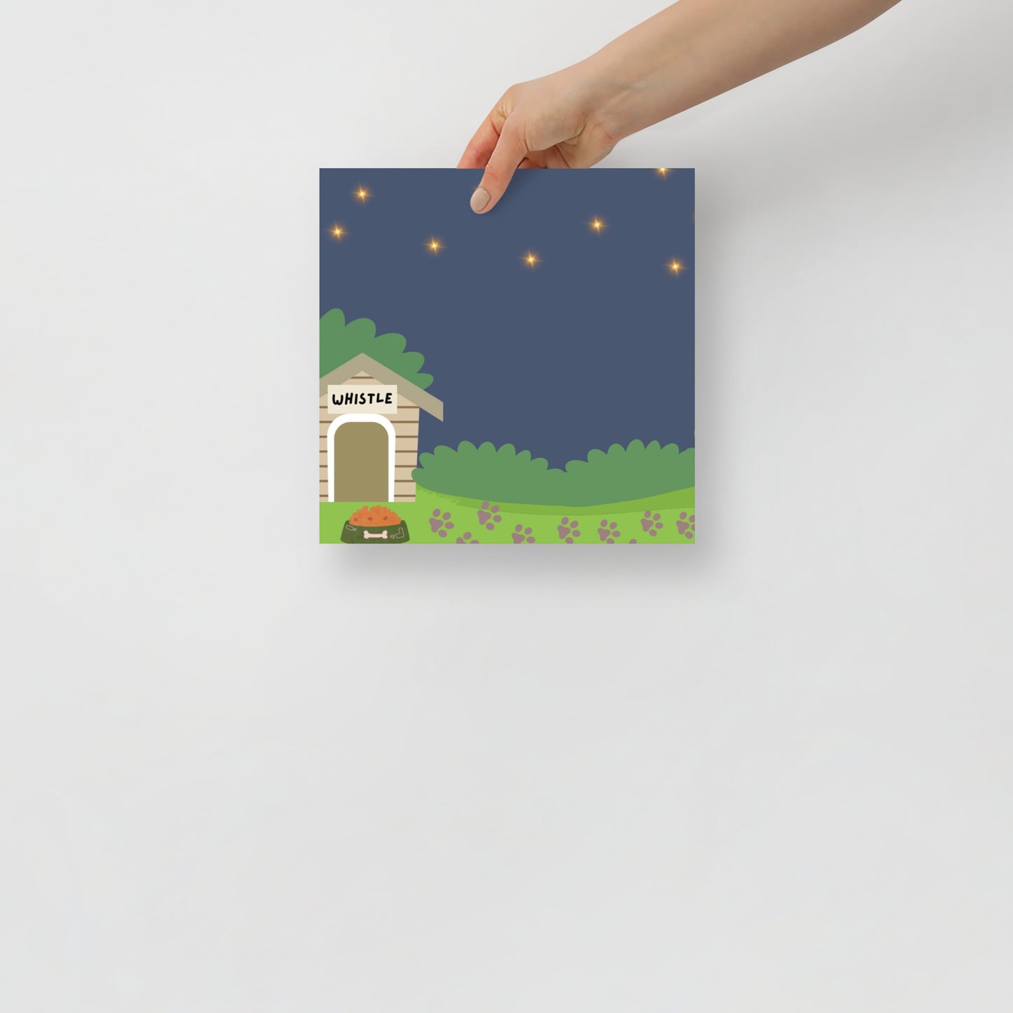 hand holding an art posters with a doghouse illustration on a white background