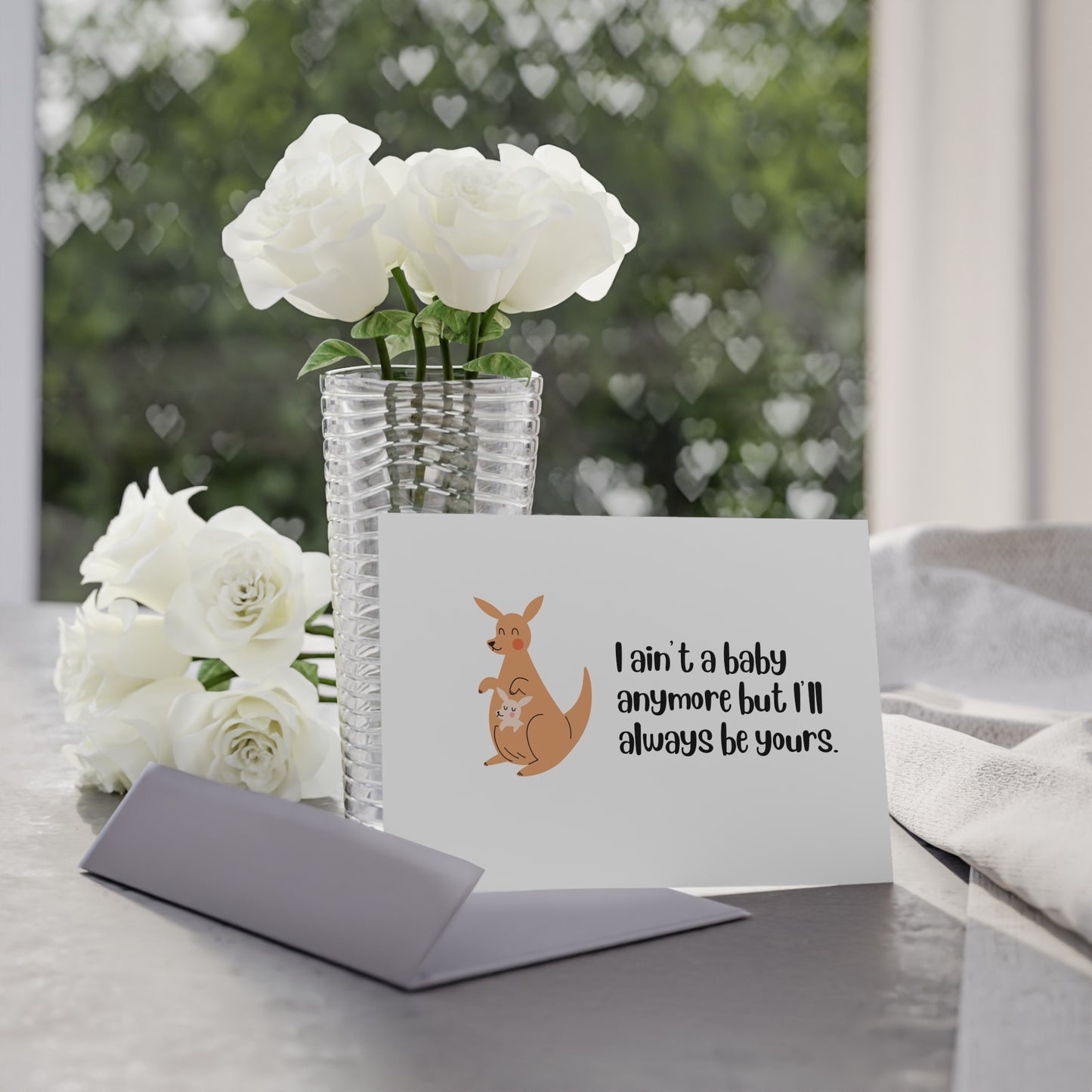 Card with kangaroo illustration and text, placed on a table with flowers in the background