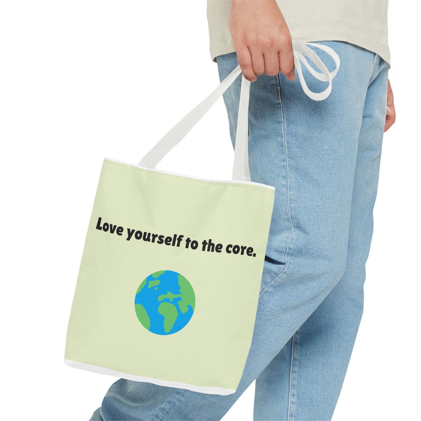 Person holding a tote bag with 'Love yourself to the core.' text and Earth graphic.