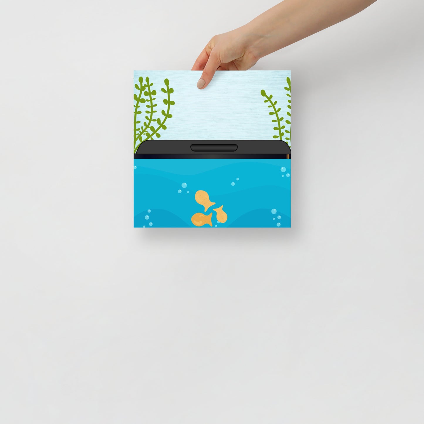 Hand holding an art poster with an aquarium design featuring goldfish and seaweed on a light grey background.