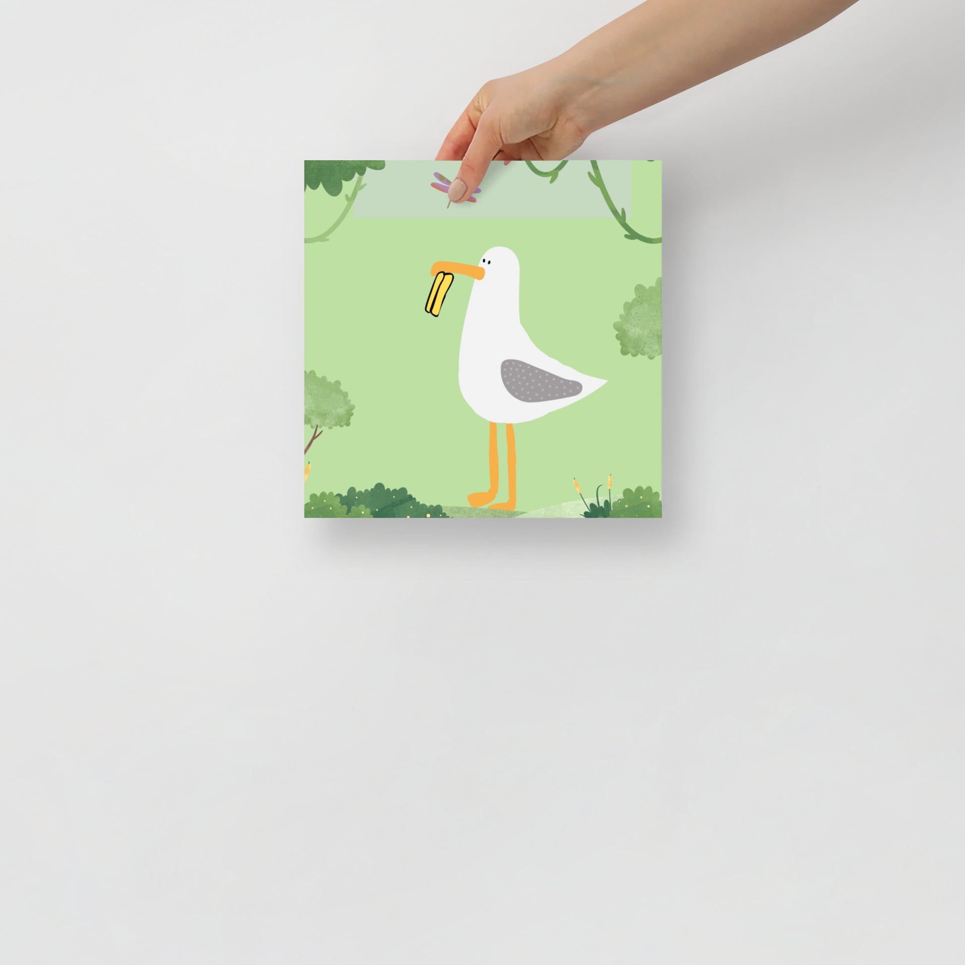 hanf holding an art poster with a seagull design on a green background with trees.