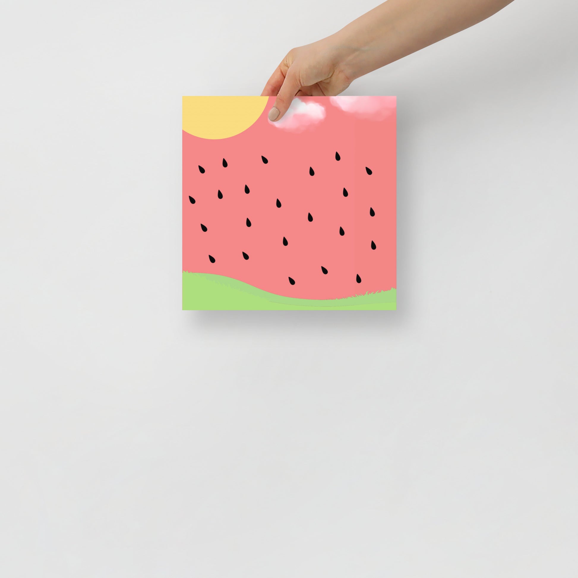 Hand holding a watermelon-themed art poster against a light pink background