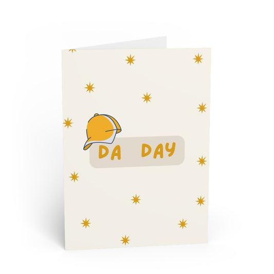 Greeting card with a yellow cap and 'DA DAY' text on a white background with yellow stars.