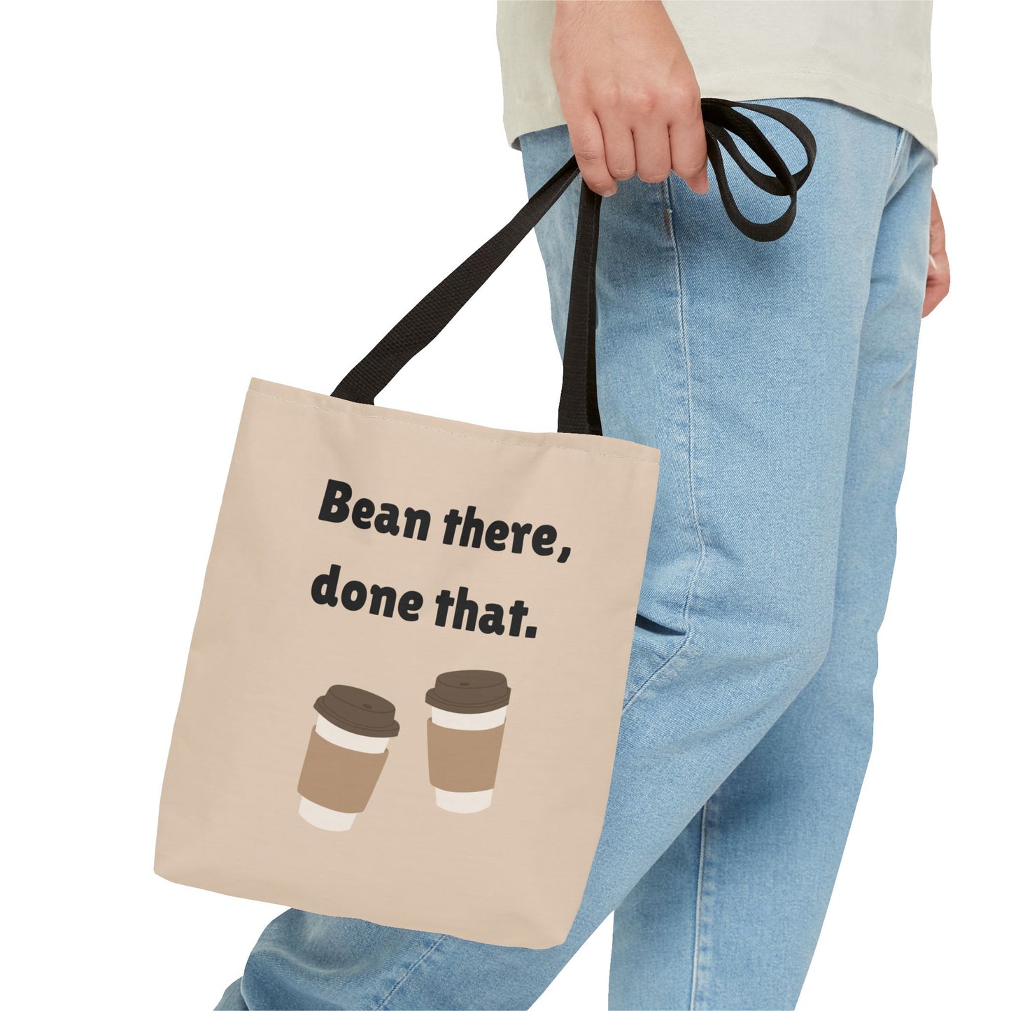 Tote bag with 'Bean there, done that.' text and coffee cup graphics held by a person wearing jeans.