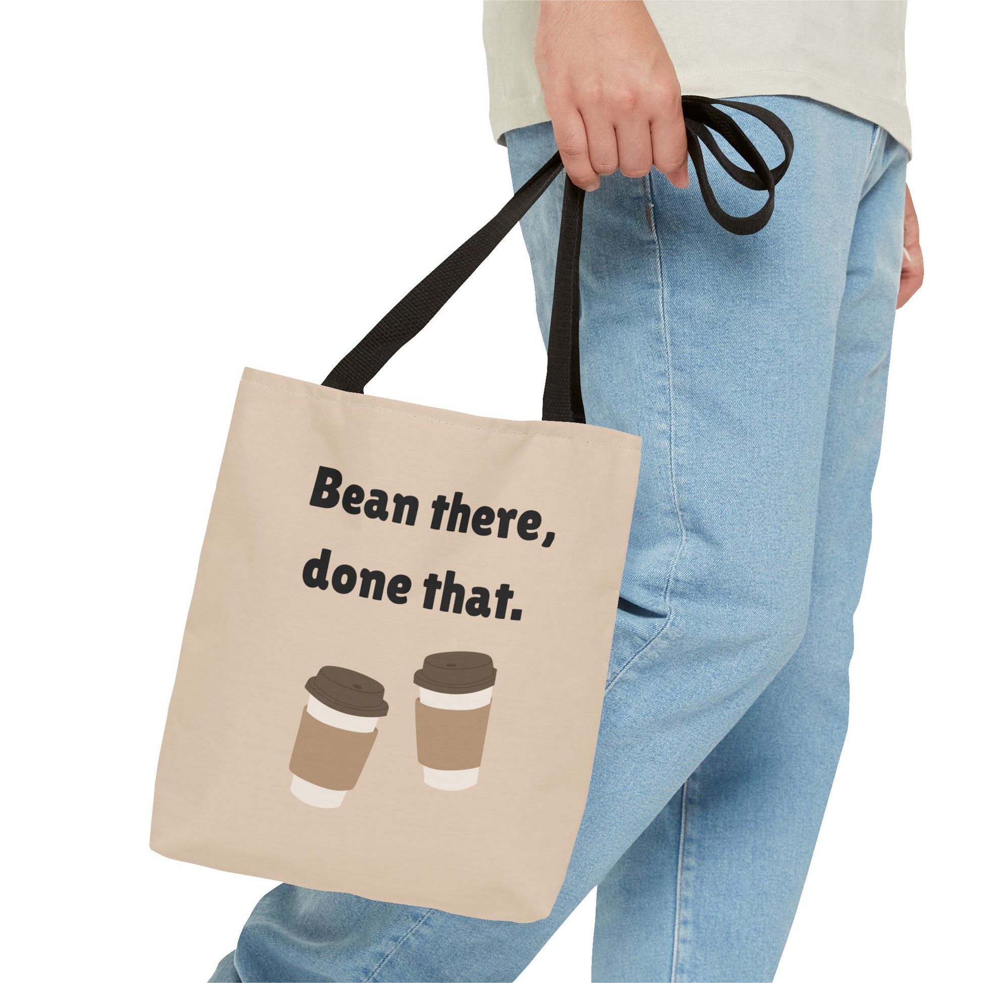 Tote bag with 'Bean there, done that.' text and coffee cup graphics held by a person wearing jeans.