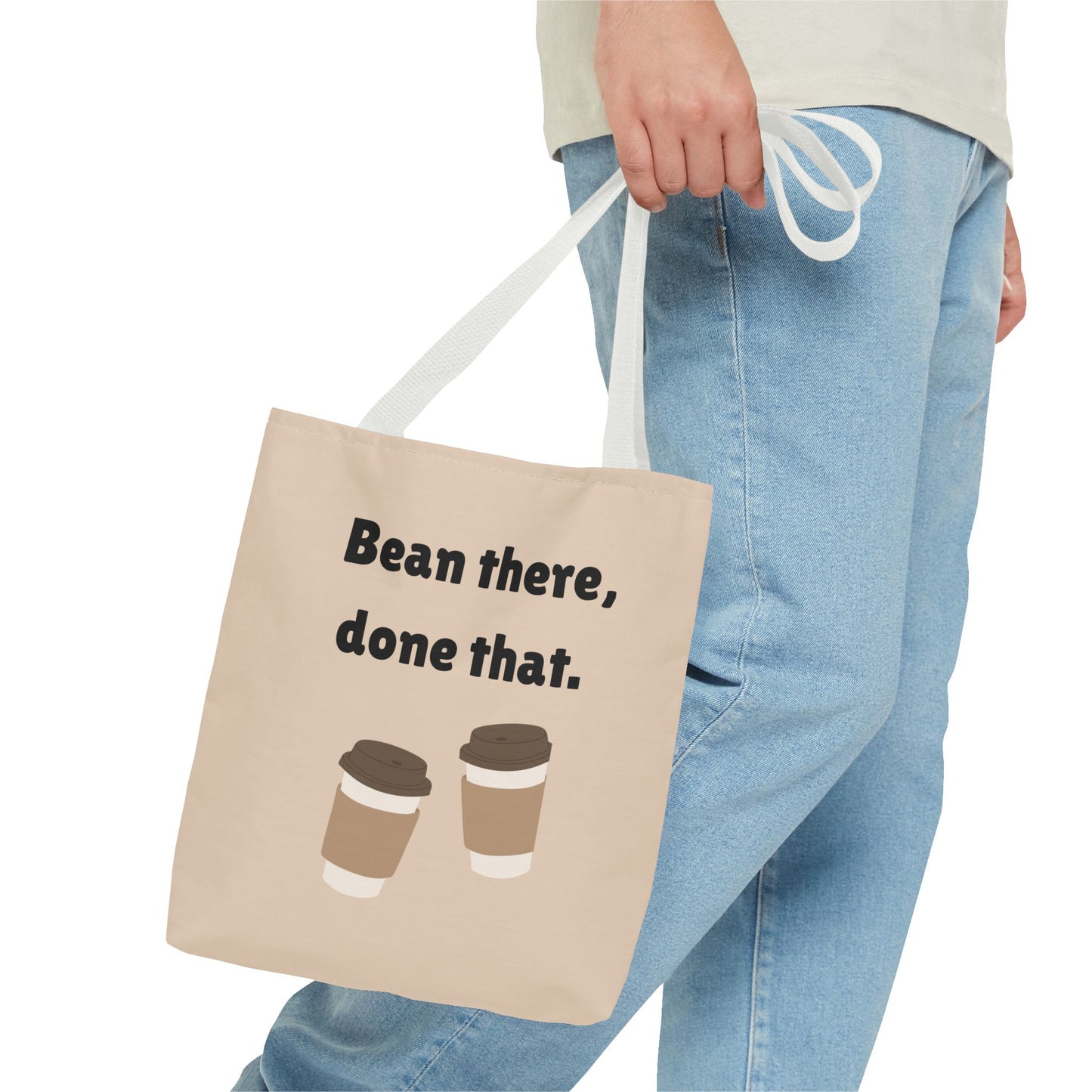 Tote bag with 'Bean there, done that.' text and coffee cup graphics held by a person wearing jeans.